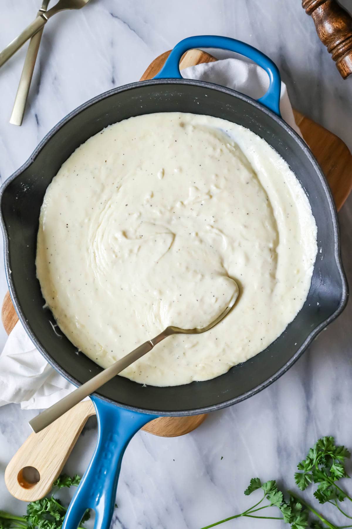 Overhead view of thickened alfredo sauce cooking in a skillet.