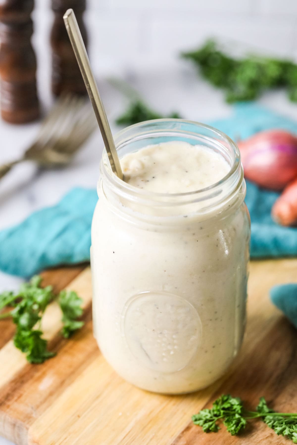 Mason jar of alfredo sauce on a wood cutting board.