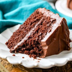 Slice of chocolate cake with one bite missing on a white plate.