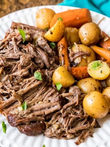 Plate of beef pot roast with baby potatoes and carrots.
