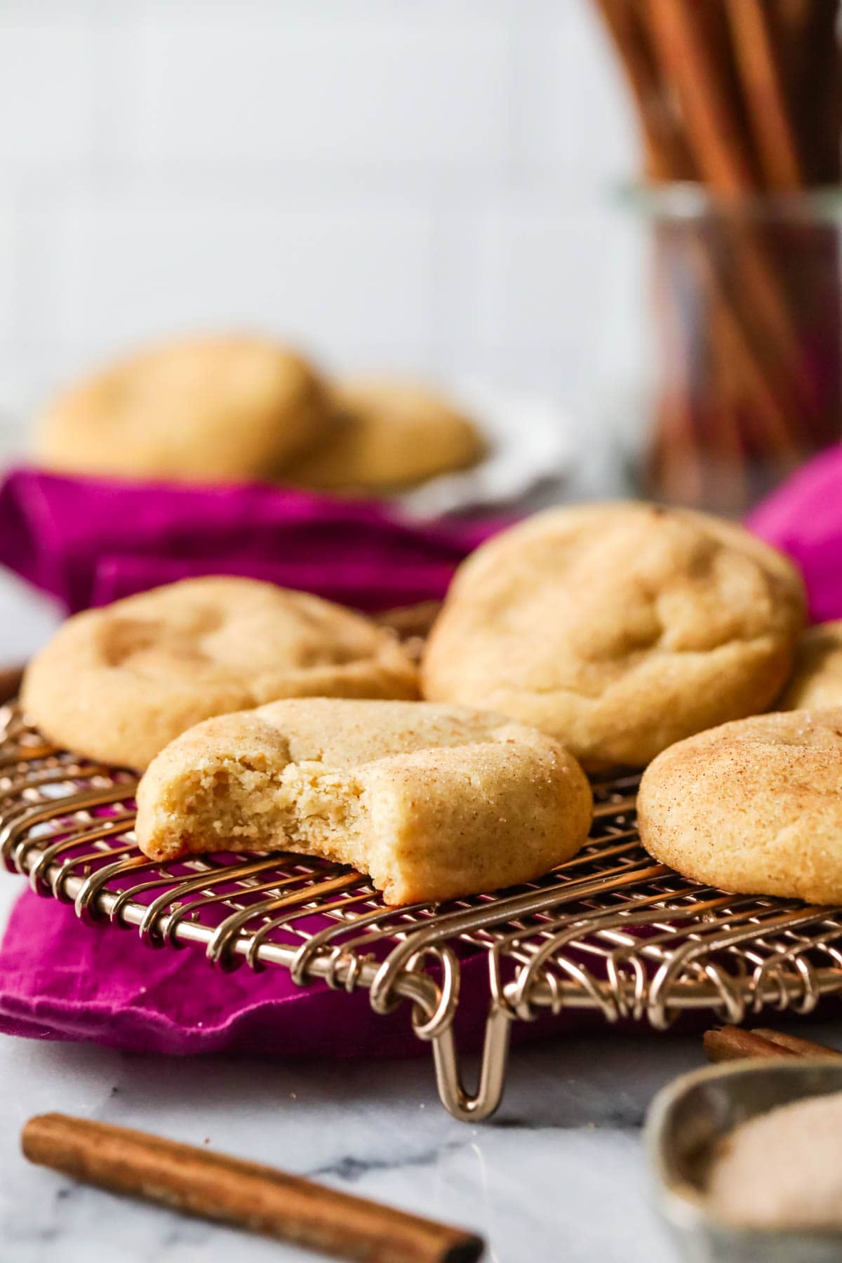 Brown butter snickerdoodles on a cooling rack with the closest cookie missing a bite.
