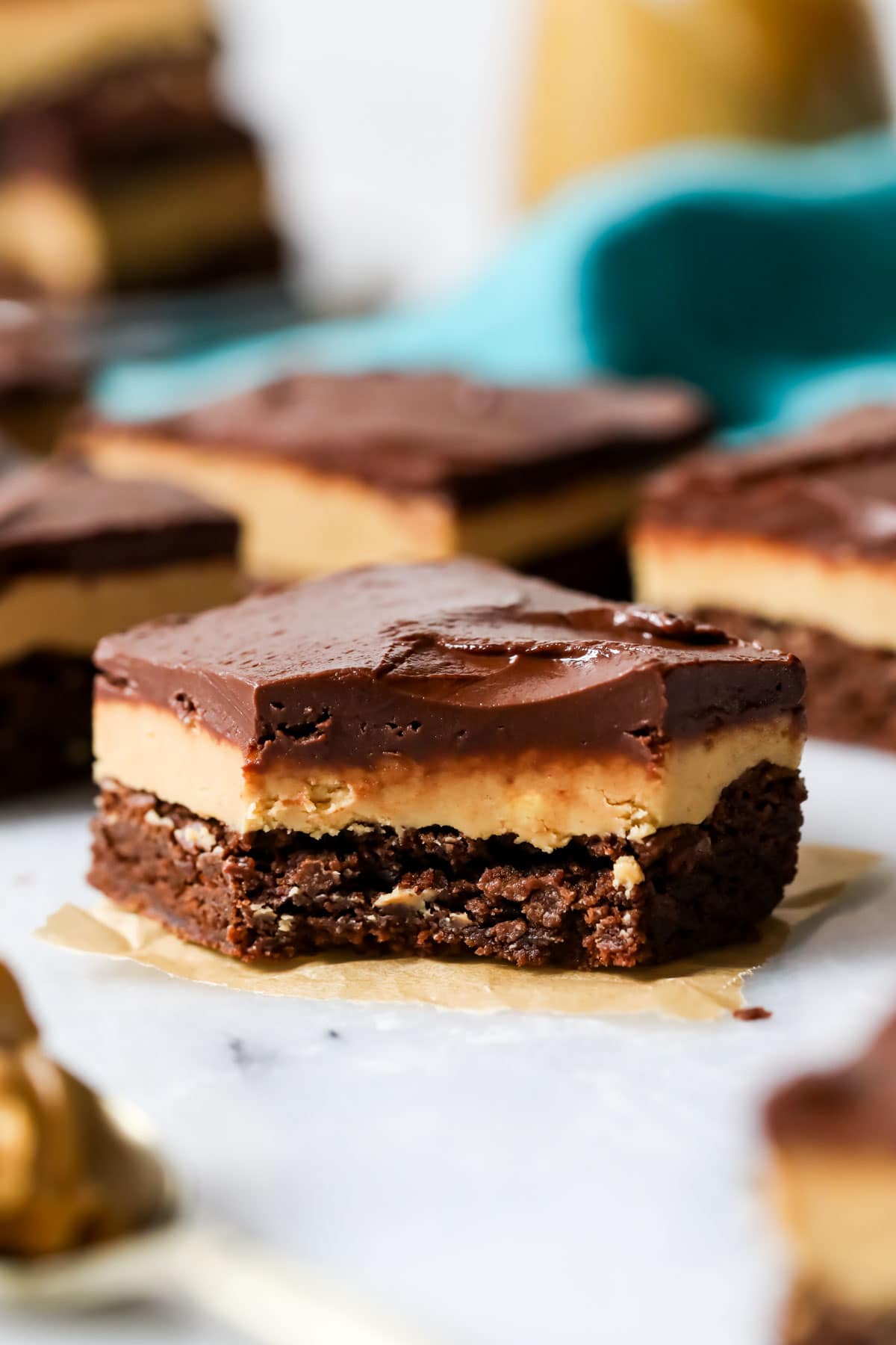 Brownie with a layer of peanut butter fudge and chocolate on top missing one bite.