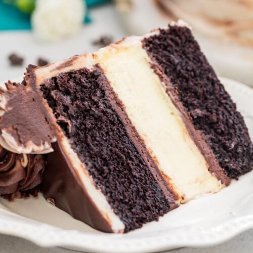 slice of cheesecake stuffed cake with clear, defined layers of dark chocolate cake and classic cheesecake on a white plate