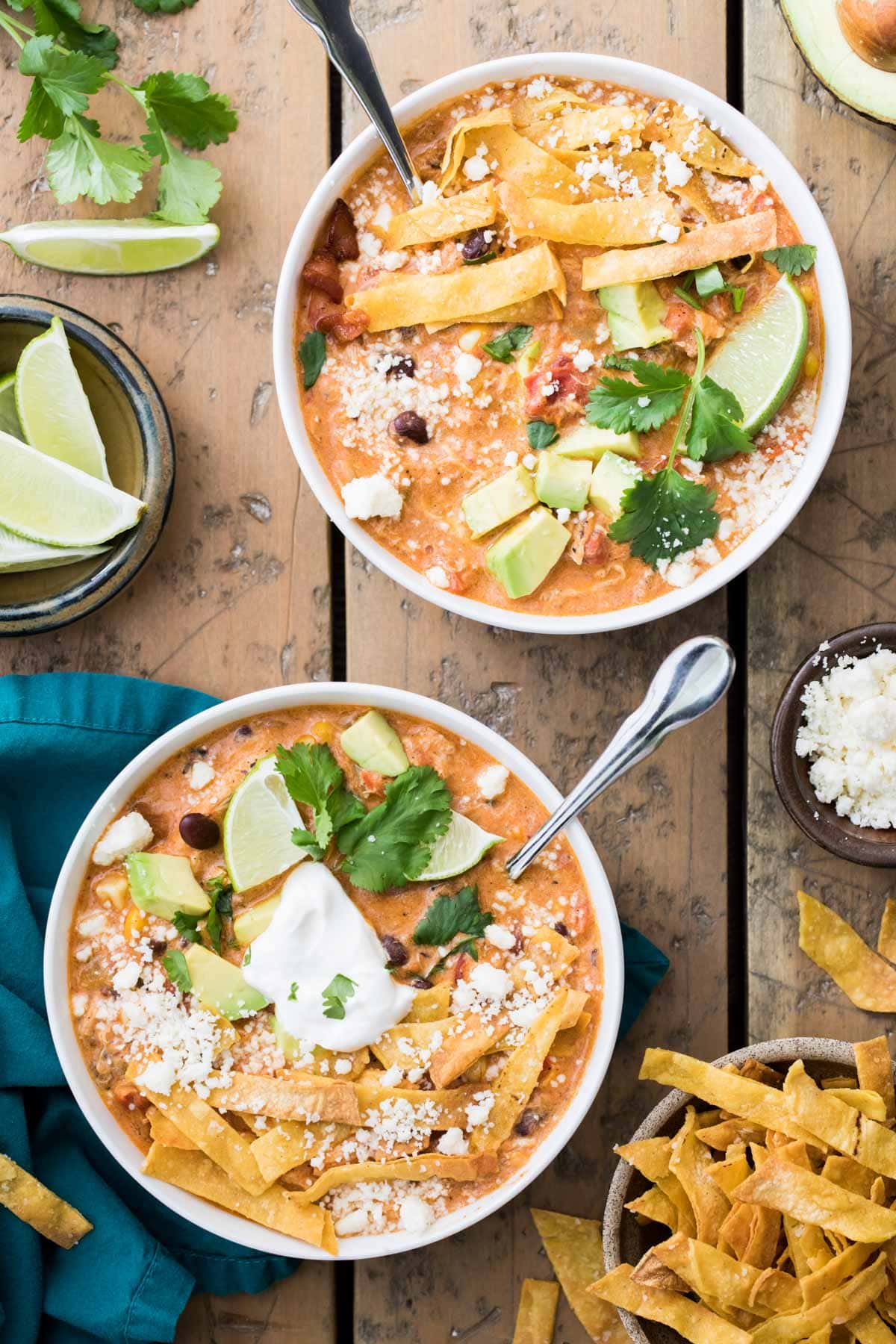 overhead of two bowls of chicken tortilla soup with toppings