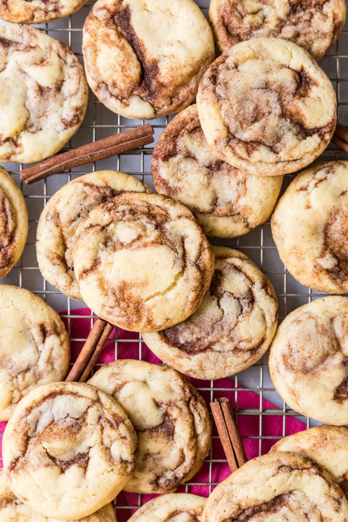 Overhead view of cinnamon cookies on a cooling rack with cinnamon sticks here and there.