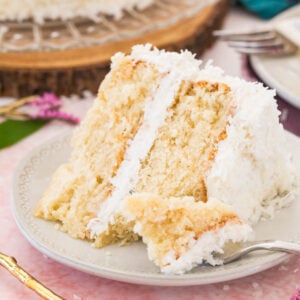 Slice of coconut cake on a plate with a forkful missing