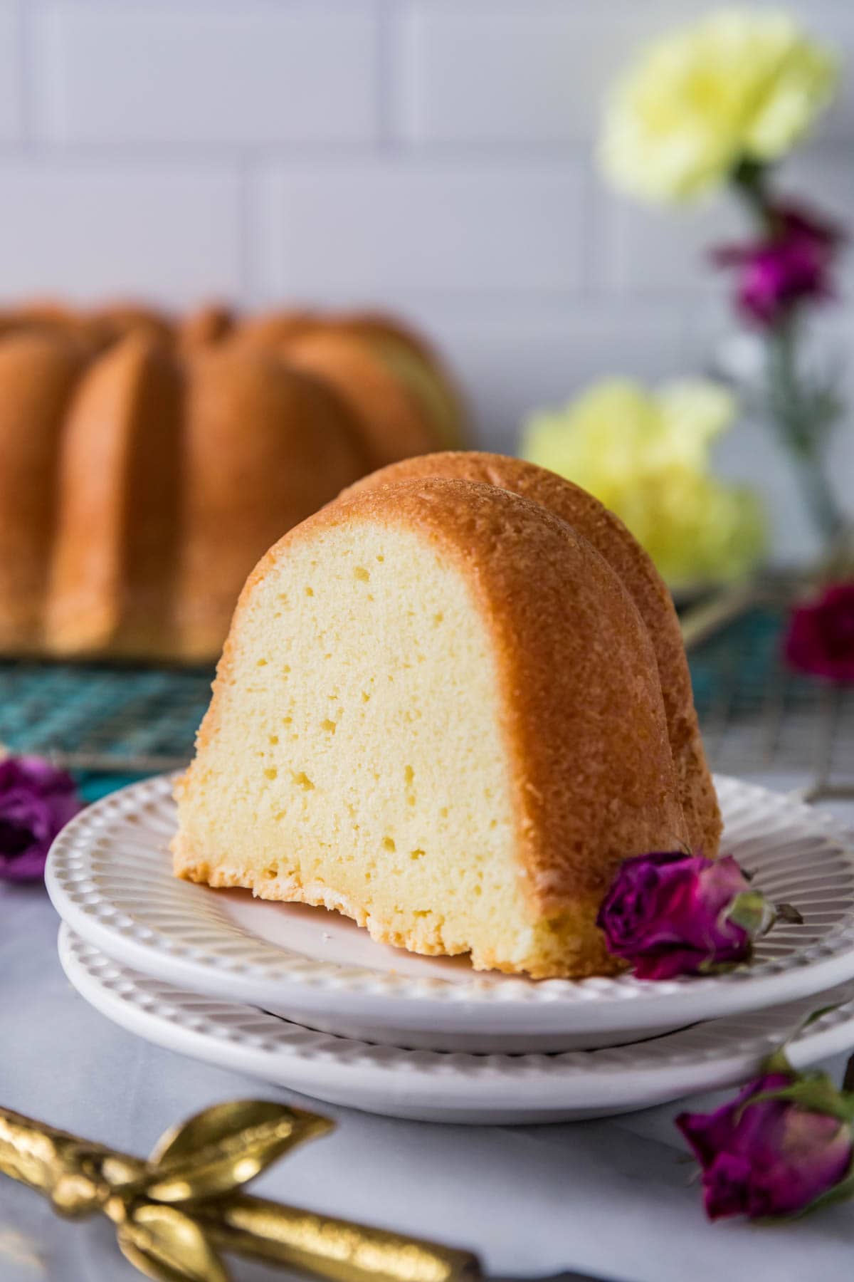 Slice of pound cake on a plate with the remaining cake in the background.