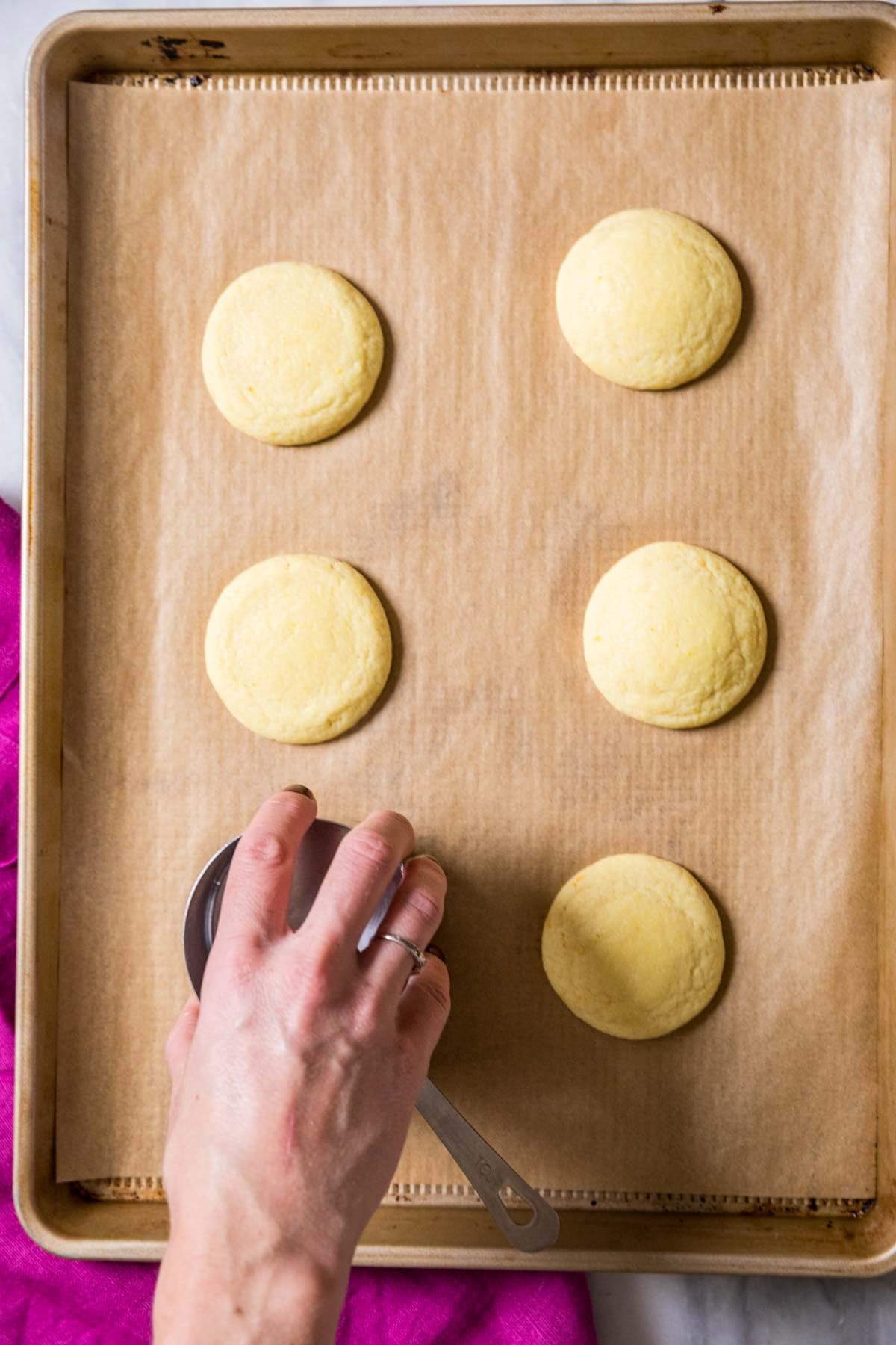 Overhead view of cookies on a baking sheet being flattened after baking.