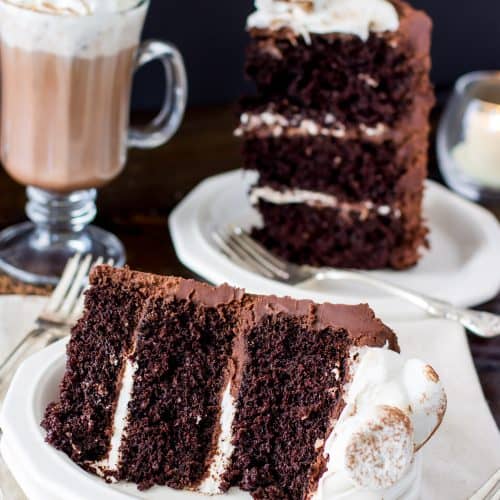 Slice of hot chocolate cake topped with marshmallows with a mug of hot chocolate in the background