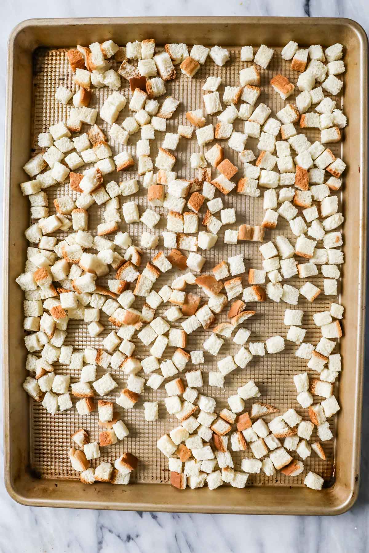 Overhead view of bread cubes for stuffing on a baking tray.