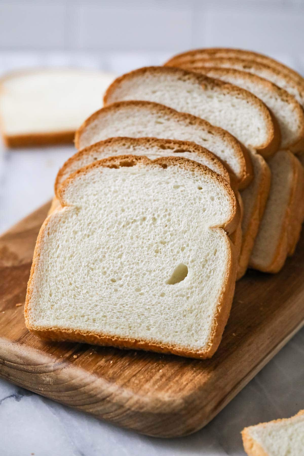 Slices of white bread on a wood cutting board.
