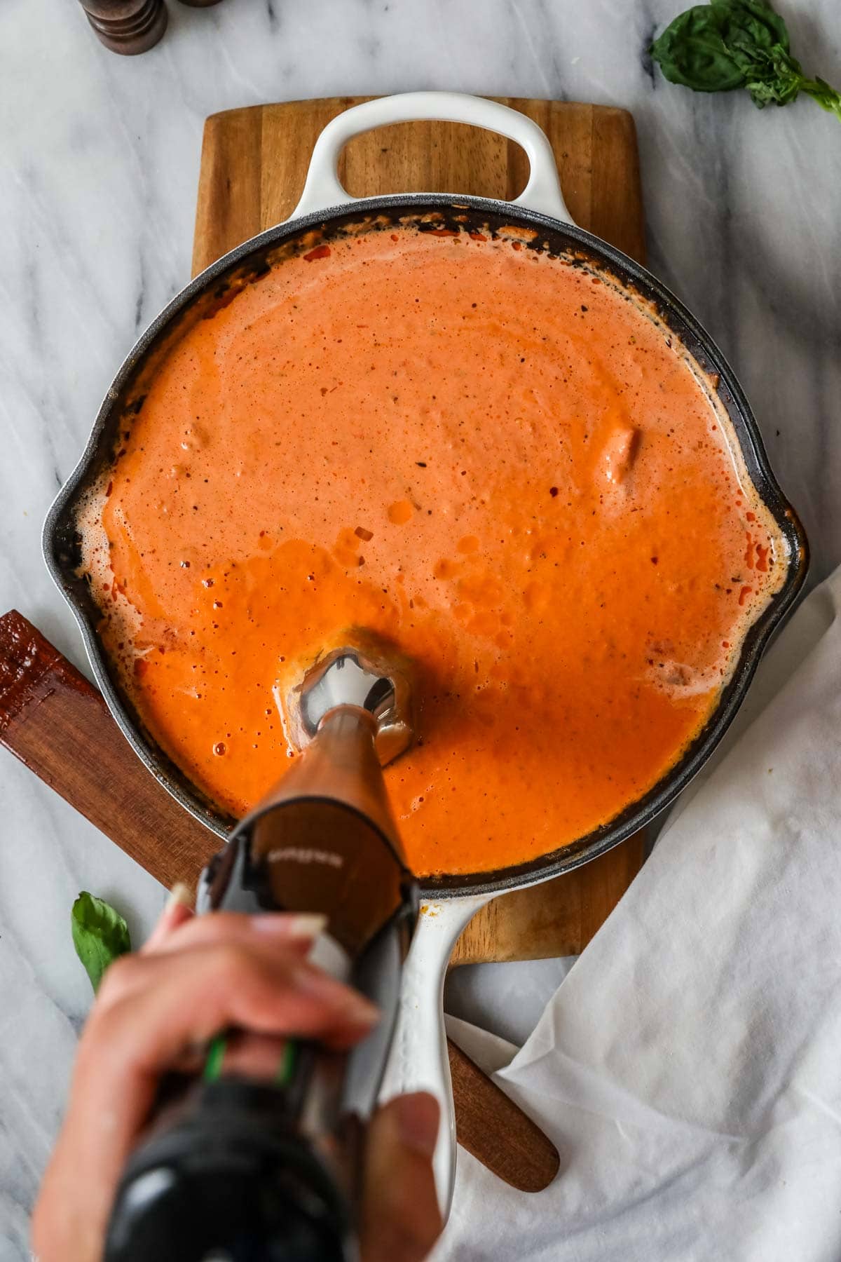 Overhead view of an immersion blender blending pasta sauce.
