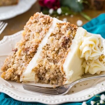 Slice of cream cheese frosted hummingbird cake on a white plate