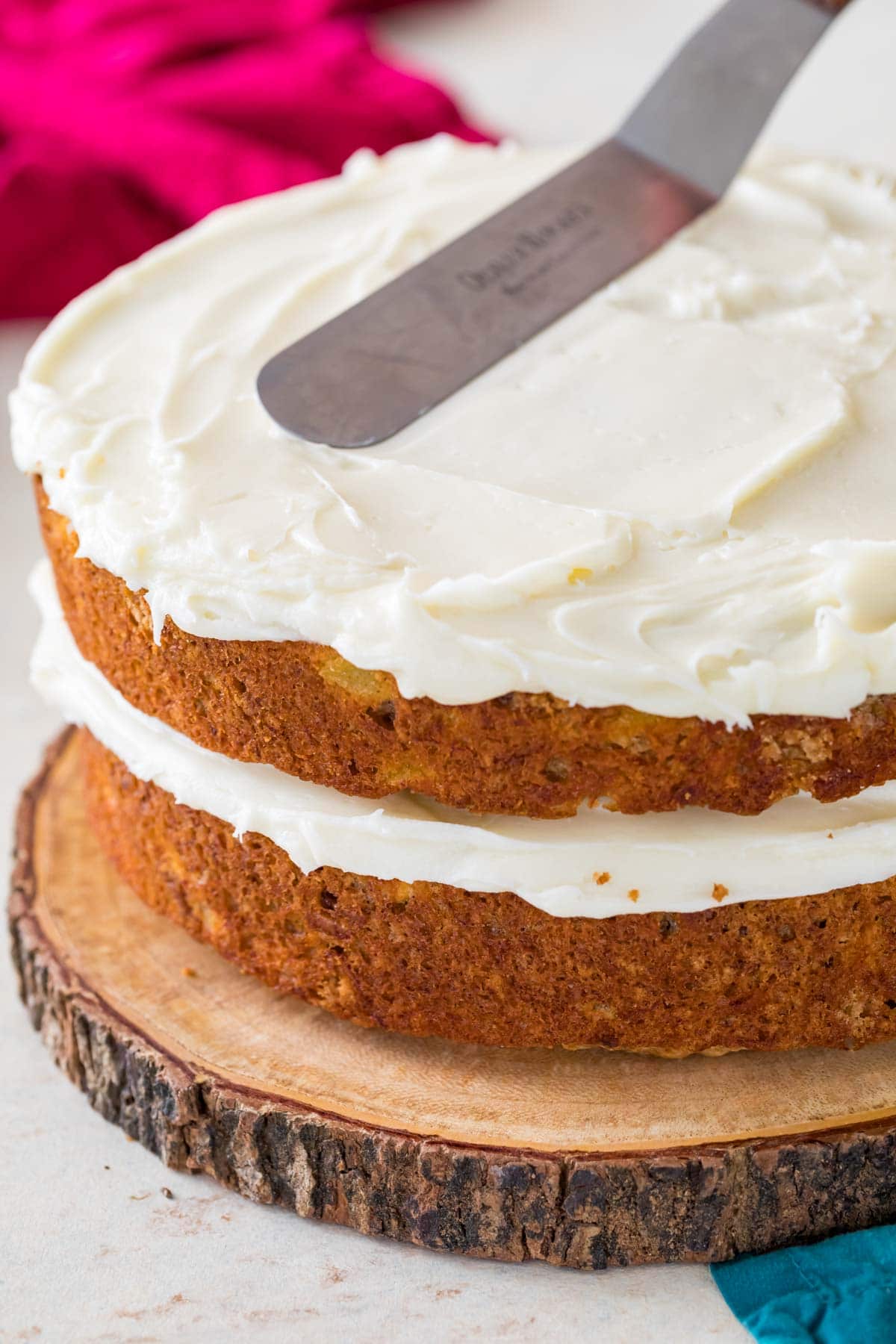 Frosting two layers of hummingbird cake with cream cheese frosting