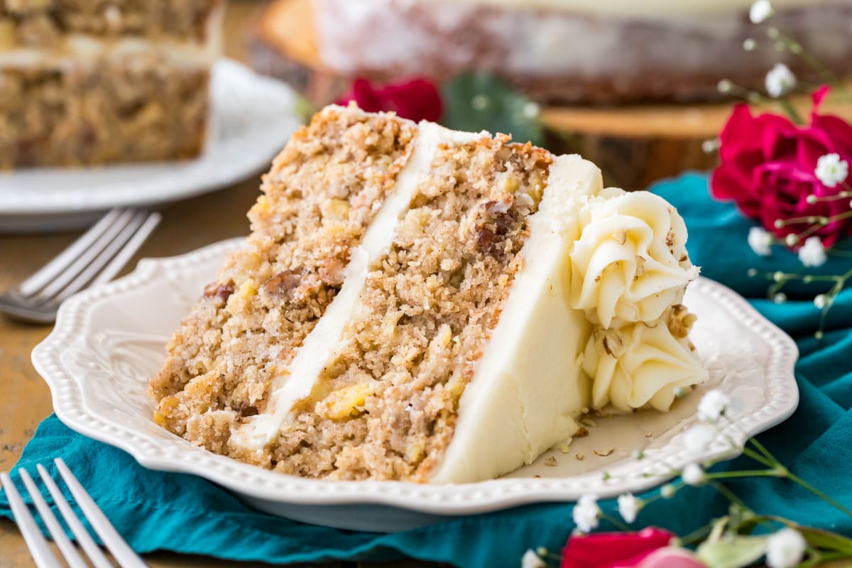 Slice of moist hummingbird cake on white plate, showcasing all the add-ins in the crumb