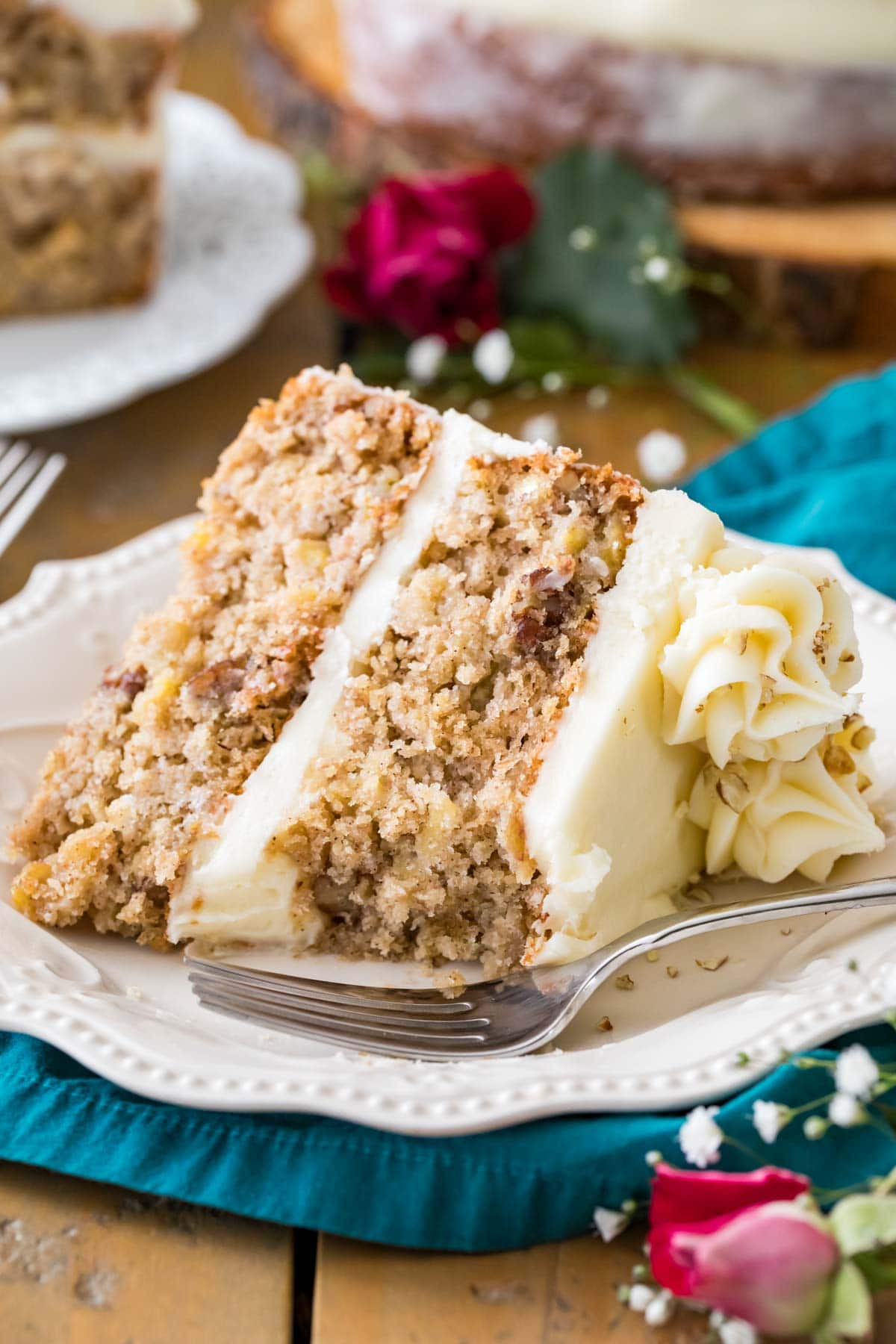 Slice of cream cheese frosted hummingbird cake on a white plate