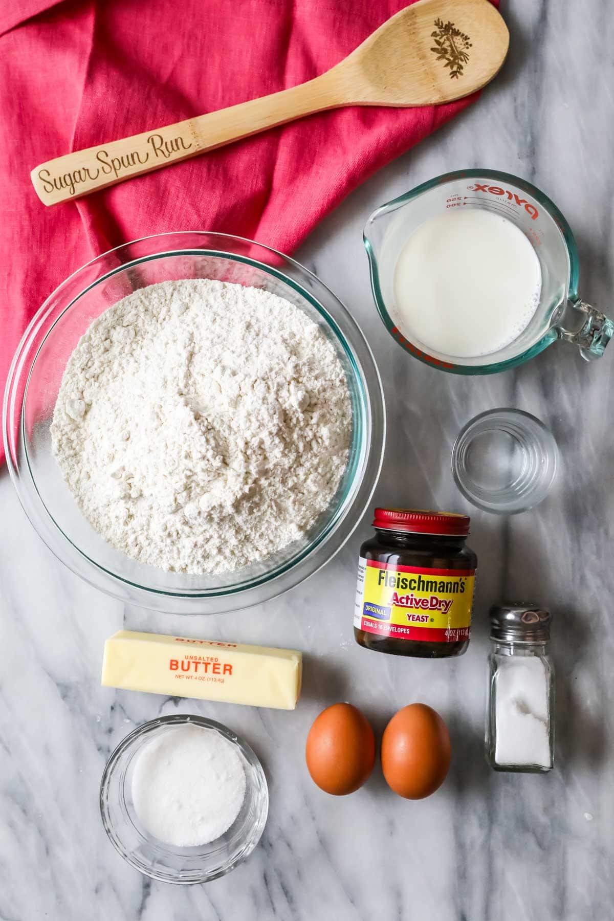 Overhead view of ingredients including yeast, bread flour, butter, and more.