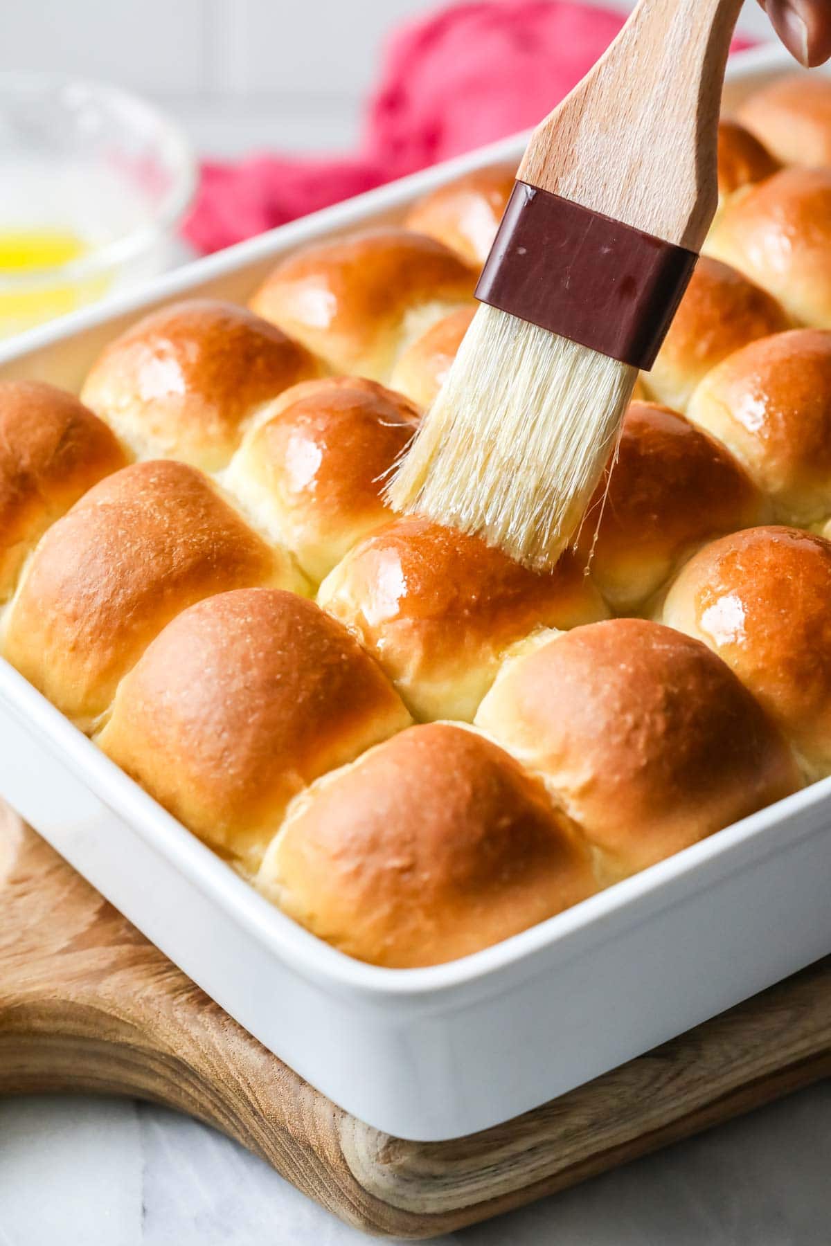 Melted butter being brushed onto make ahead dinner rolls.