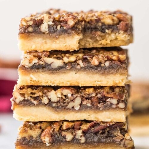 four pecan pies stacked on top of each other, with the top bar missing one bite