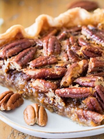 Slice of pecan pie on a white plate.