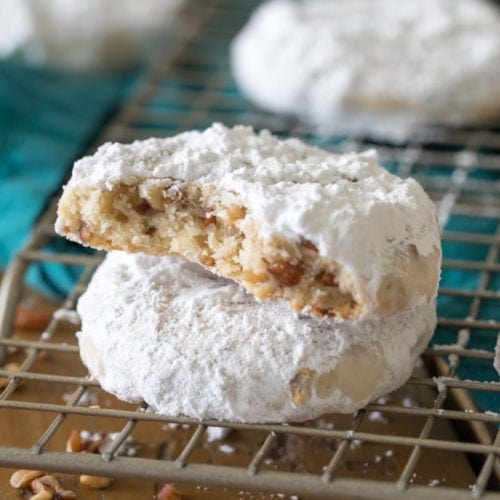 Pecan sandies stacked on top of each other on wire cooling rack with bite taken out.