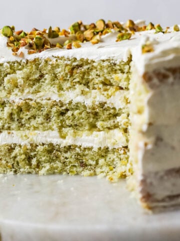 Cross section of a pistachio cake made with three layers of green cake and a swiss meringue buttercream frosting.