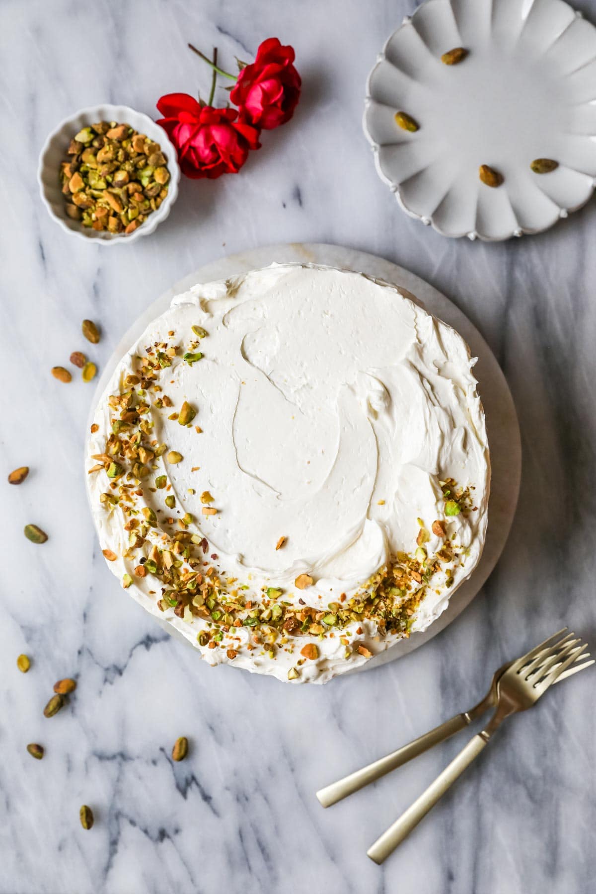 Overhead view of a cake decorated with a border of chopped pistachios around half of the cake.