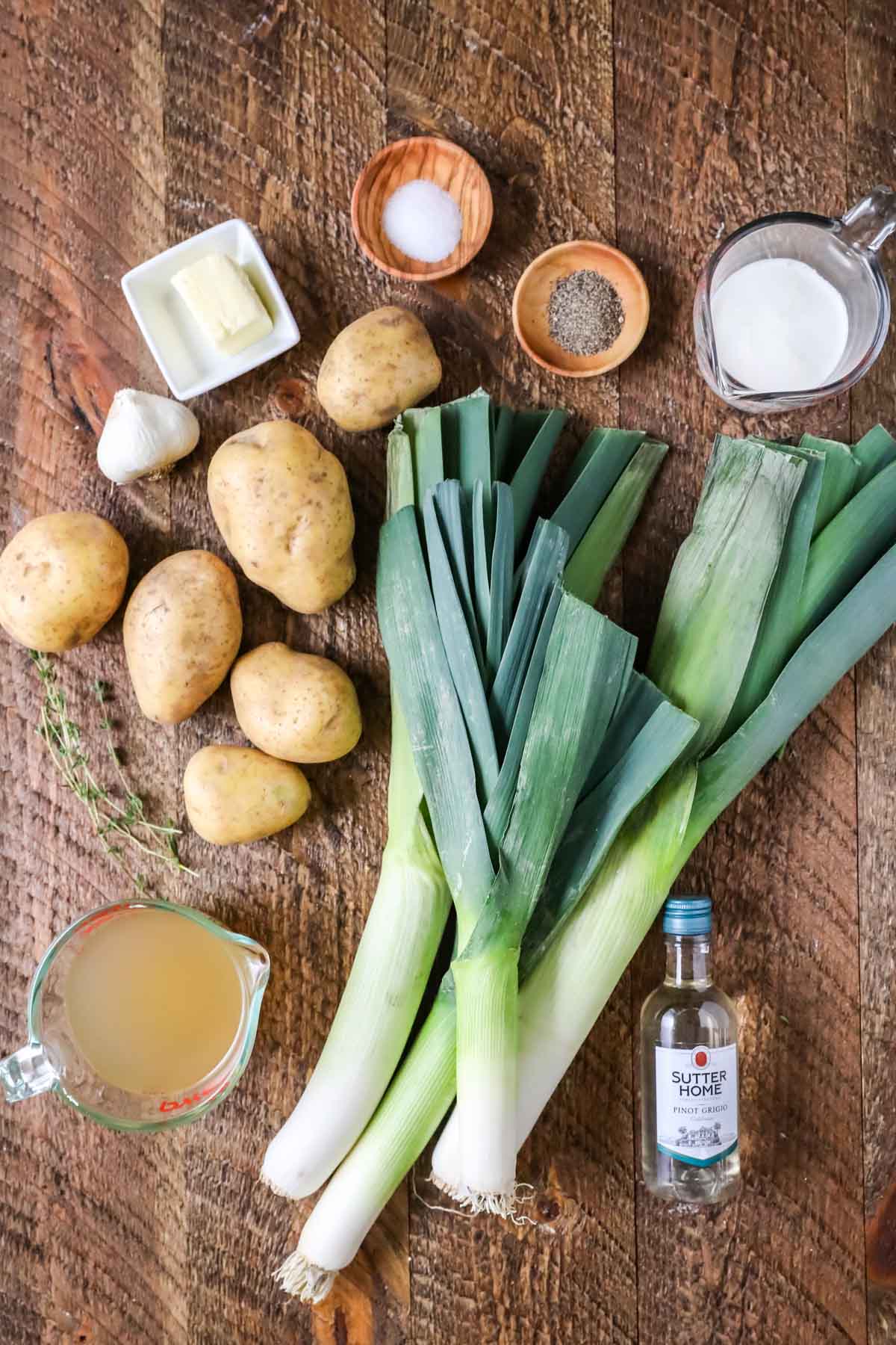 Overhead view of ingredients including leeks, gold potatoes, chicken broth, wine, and more.