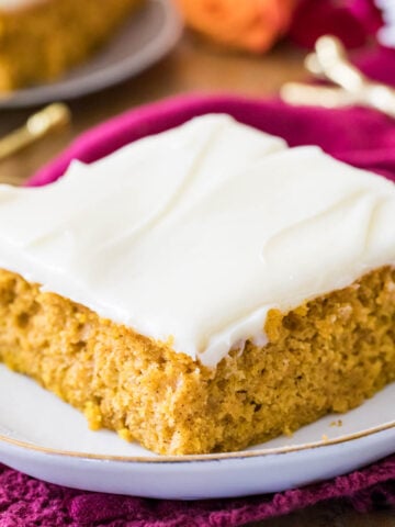Pumpkin bar frosted with cream cheese frosting on a white plate.