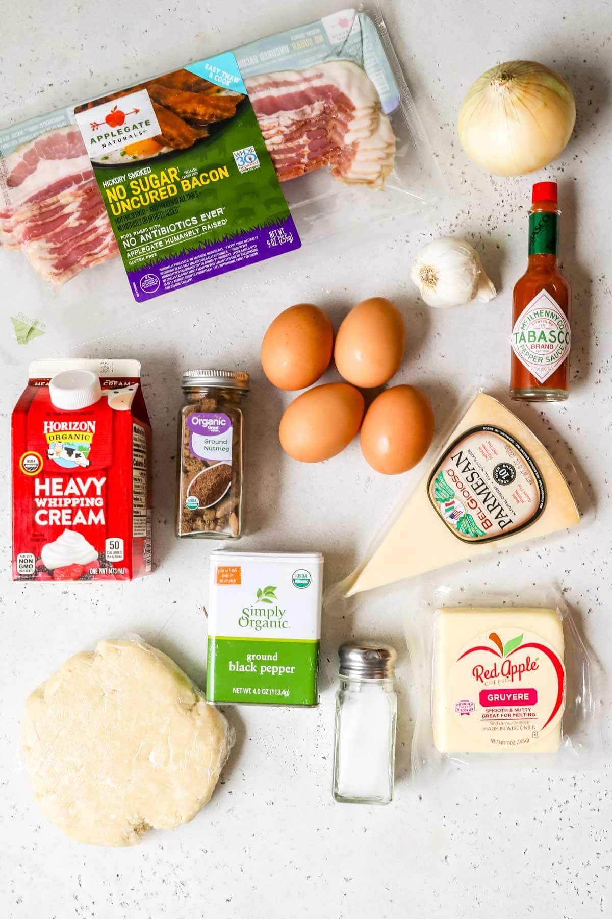 Overhead view of ingredients including parmesan cheese, eggs, bacon, and more.