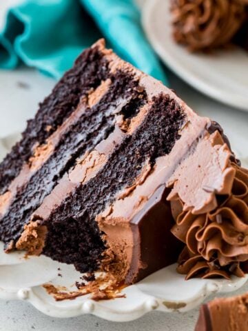 Slice of triple chocolate cake missing a bite on a white plate.