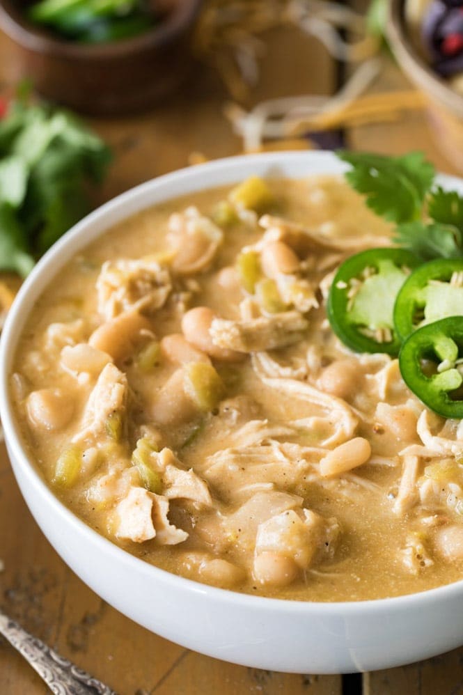 A white bowl of chicken chili topped with jalapeno slices