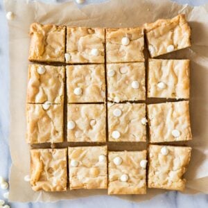 Overhead view of a batch of white chocolate brownies cut into 16 pieces.